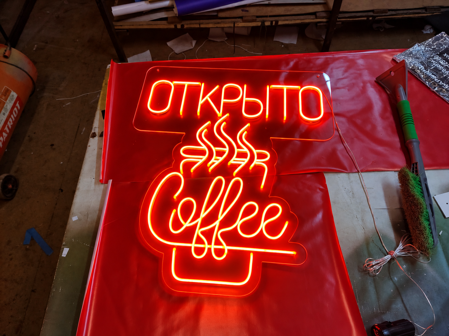 Неоновая вывеска «Открыто / Coffee» с контуром чашки на рабочем столе
