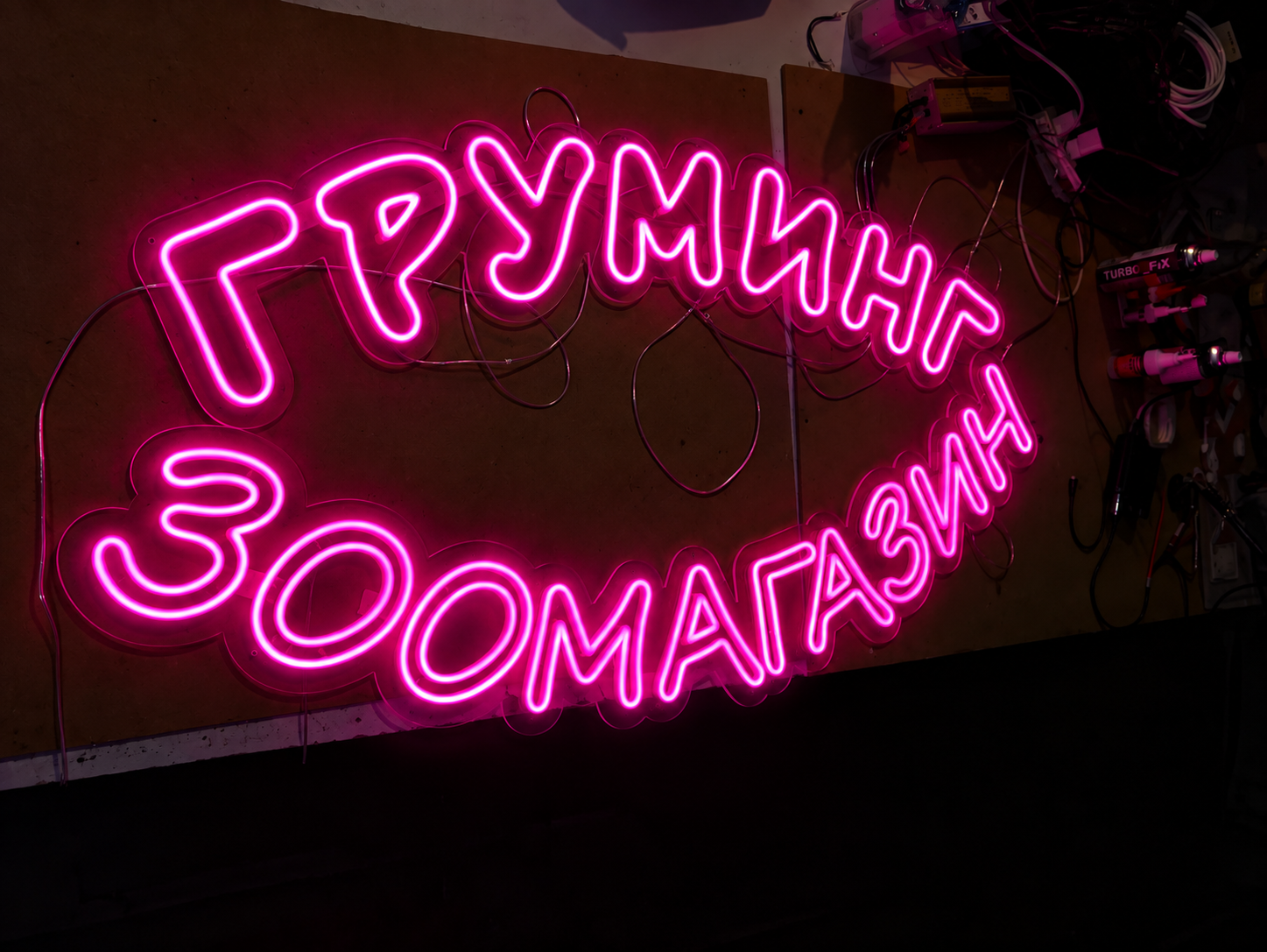 Неоновая вывеска «Груминг / Зоомагазин» на рабочем столе в мастерской